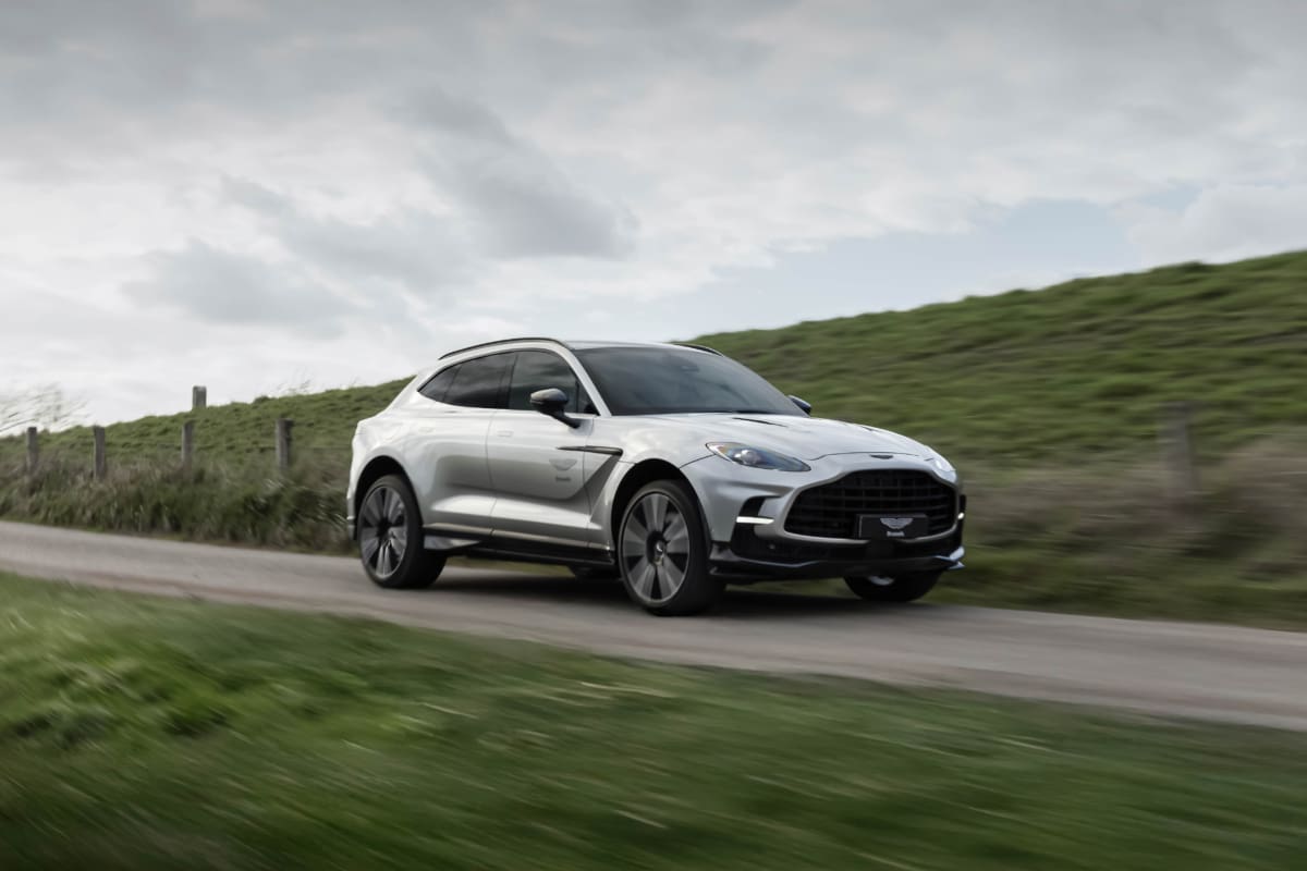 Aston Martin DBX707 driving on a countryside road in Belgium, side-front rolling view.
